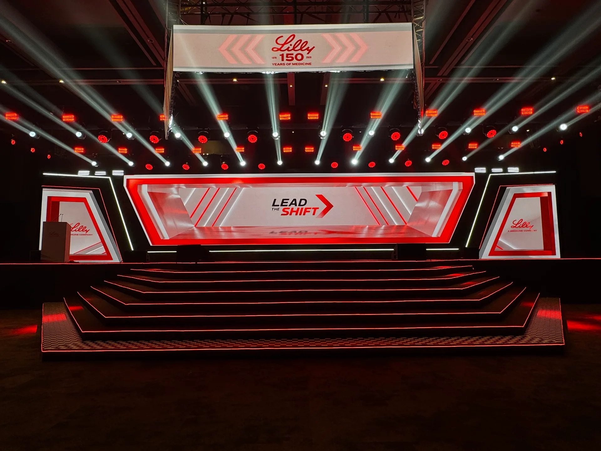 The Lead the Shift frame standing in the venue, steps lit red