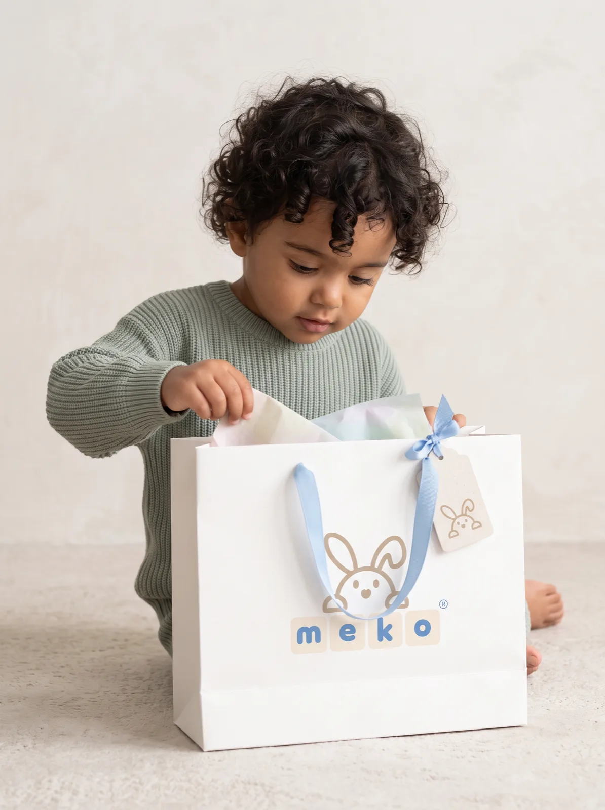 Child opening a MEKO gift bag with ribbon and tag